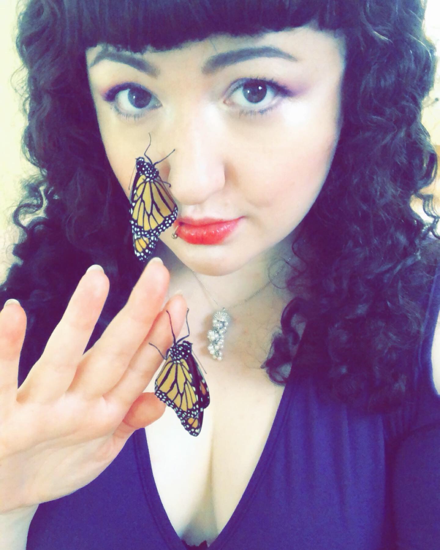 self portrait of the site creator. Pale woman with dark curly brown hair, holding monach butterflies